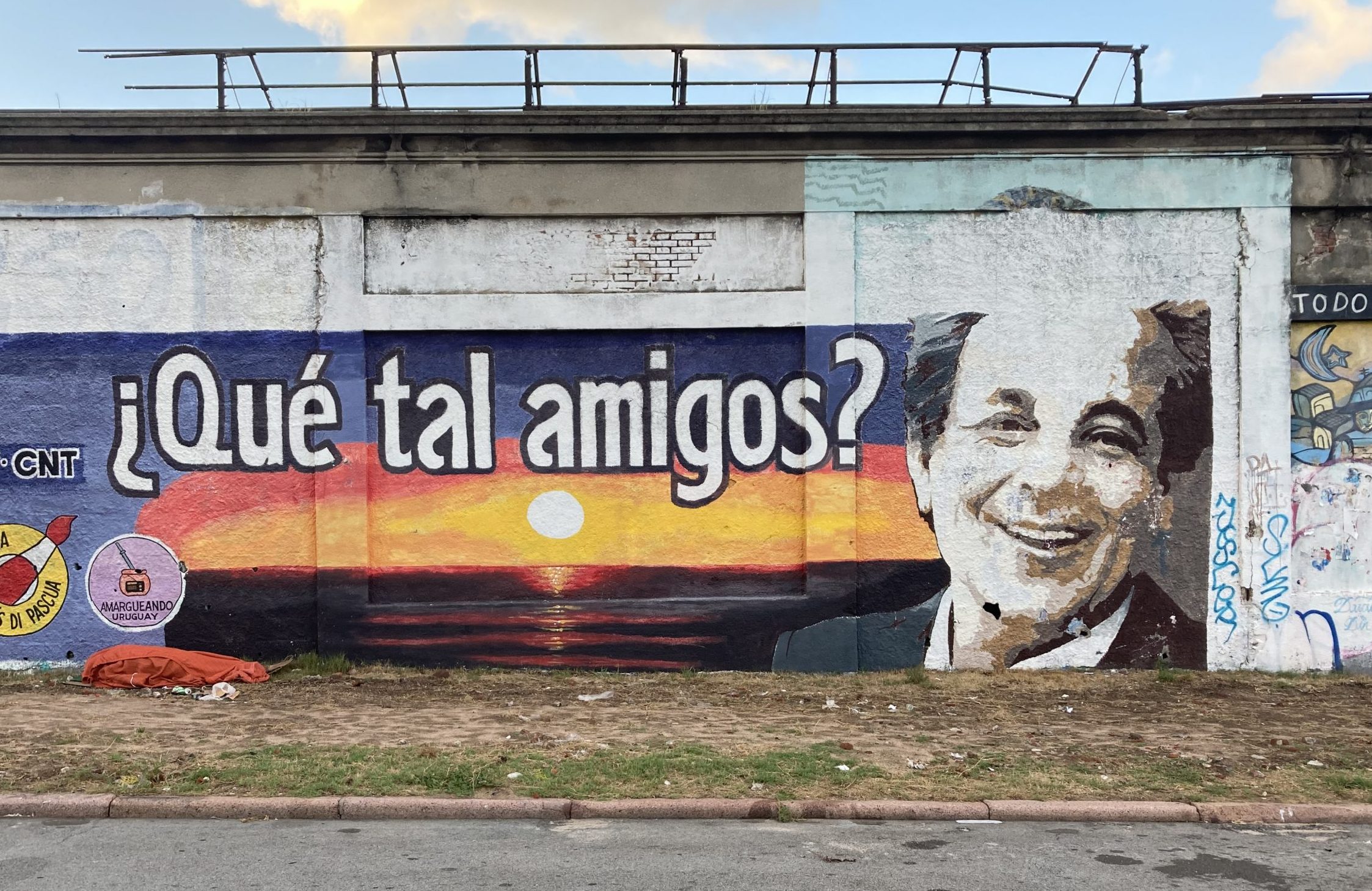 WAndbild mit einem Sonnen untergang und einem Gesichtauf der rechten Seite und der FrageQué tal amigos! Als Schriftzug